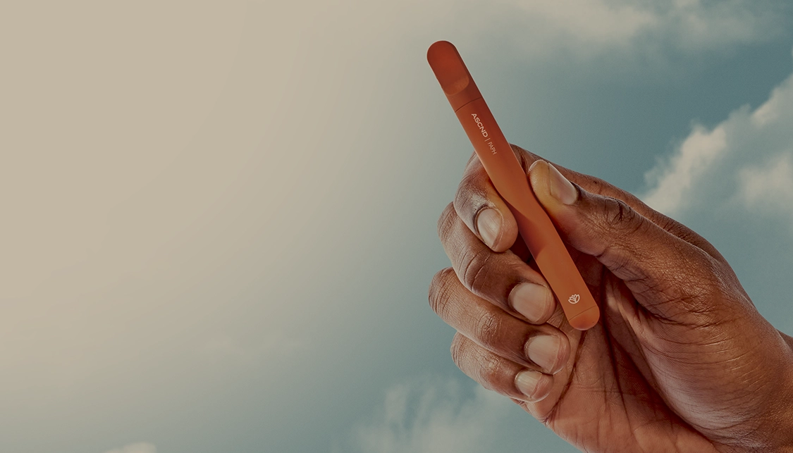 kurvana-420-header-landing | Kurvana | Curated for years. Experienced in moments. Hand holding orange vape pen against the sky background.