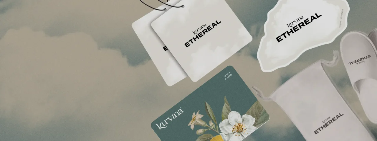 kurvana-rewards-header-02 | Kurvana | Curated for years. Experienced in moments. Kurvana Ethereal branding items: hang tags, gift card, slippers, and bag on cloudy background.